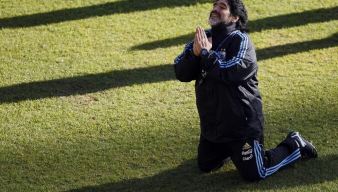 Argentina s soccer team coach Diego Maradona kneels while speaking to a journalist